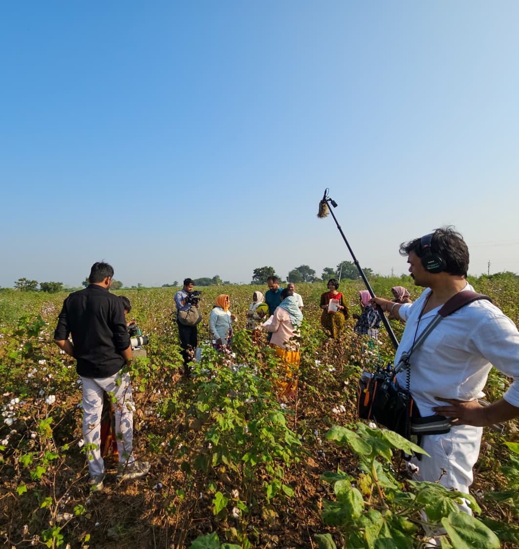 Boom microphone and lighting rig set up over a green field