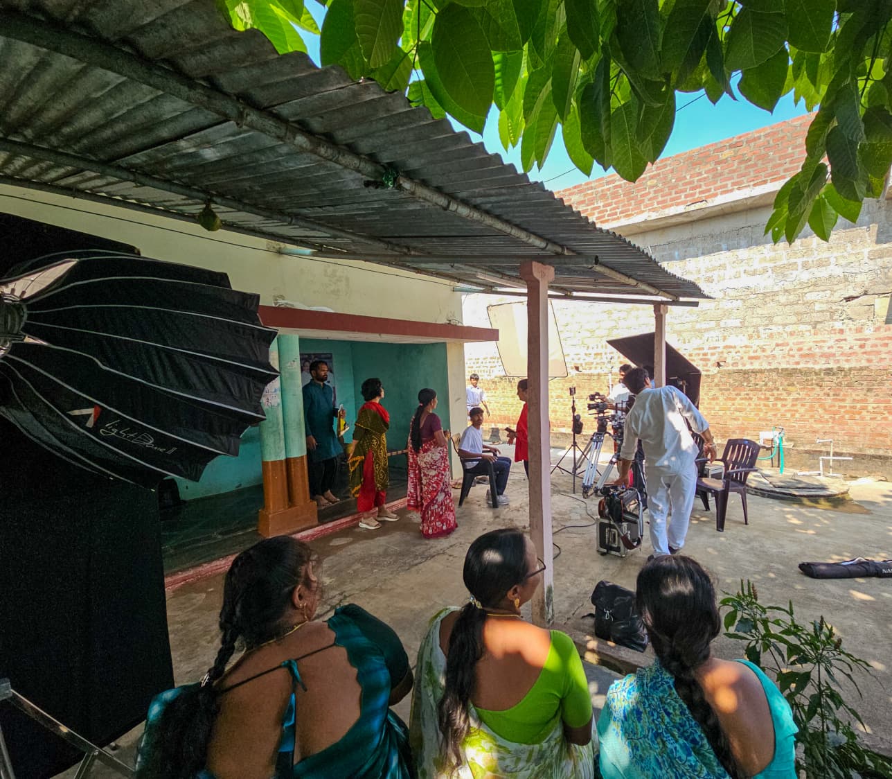 Crew filming a gathering outside a village home